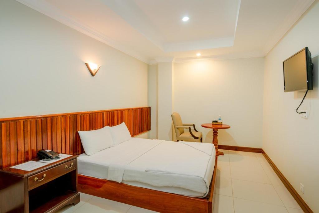 Dormitorio con cama, escritorio y TV en Holiday Hotel en Kampong Speu