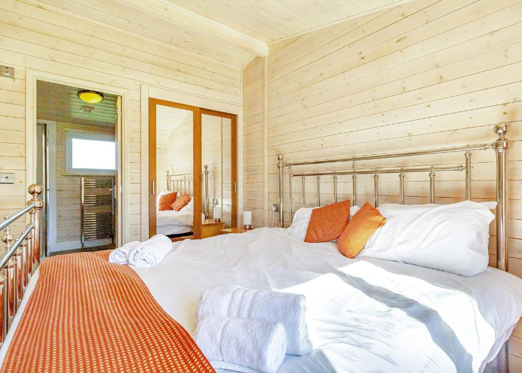 a bedroom with a large white bed with orange pillows at Messingham Lakes in Messingham