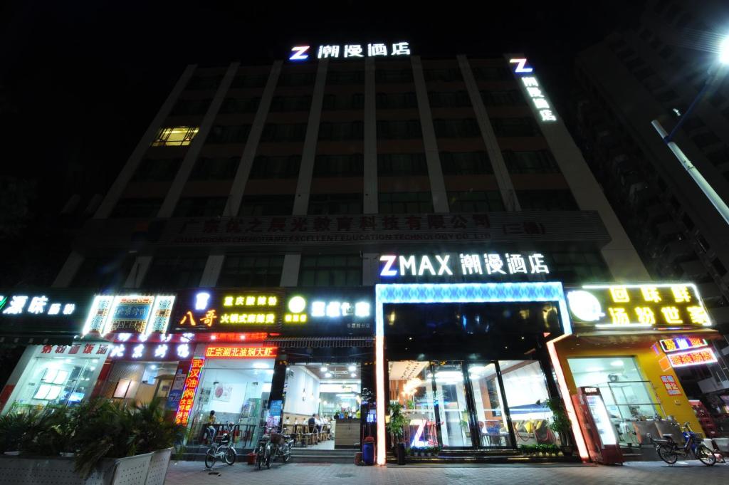 un bâtiment avec des panneaux de néon devant lui la nuit dans l'établissement Chao Man Hotel - Guangzhou Railway Station Sanyuanli Metro Station, à Canton