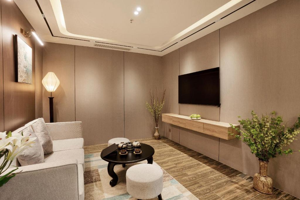 A softly lit lounge with a sofa, television and decorative seating.