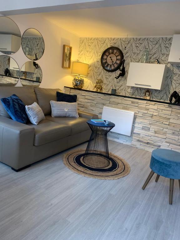 un salon avec un canapé et une horloge au mur dans l'établissement O ' Garden et sa terrasse, à Bonsecours