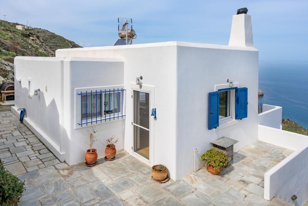 a white house with blue windows and the ocean at Blue and White in Otzias