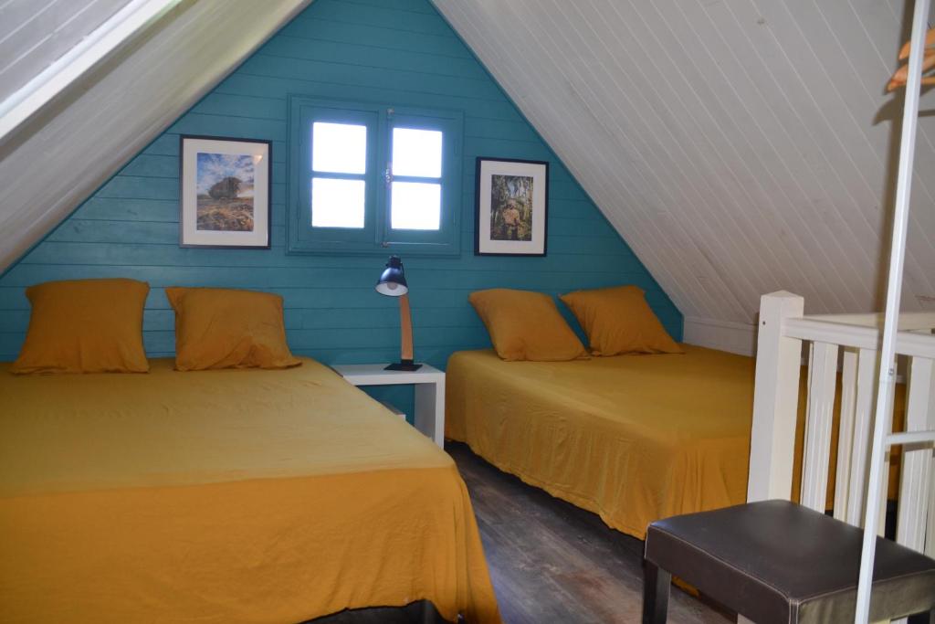 two beds in a attic room with blue walls at La Petite Kaz Dans la Savane in Fleurimont