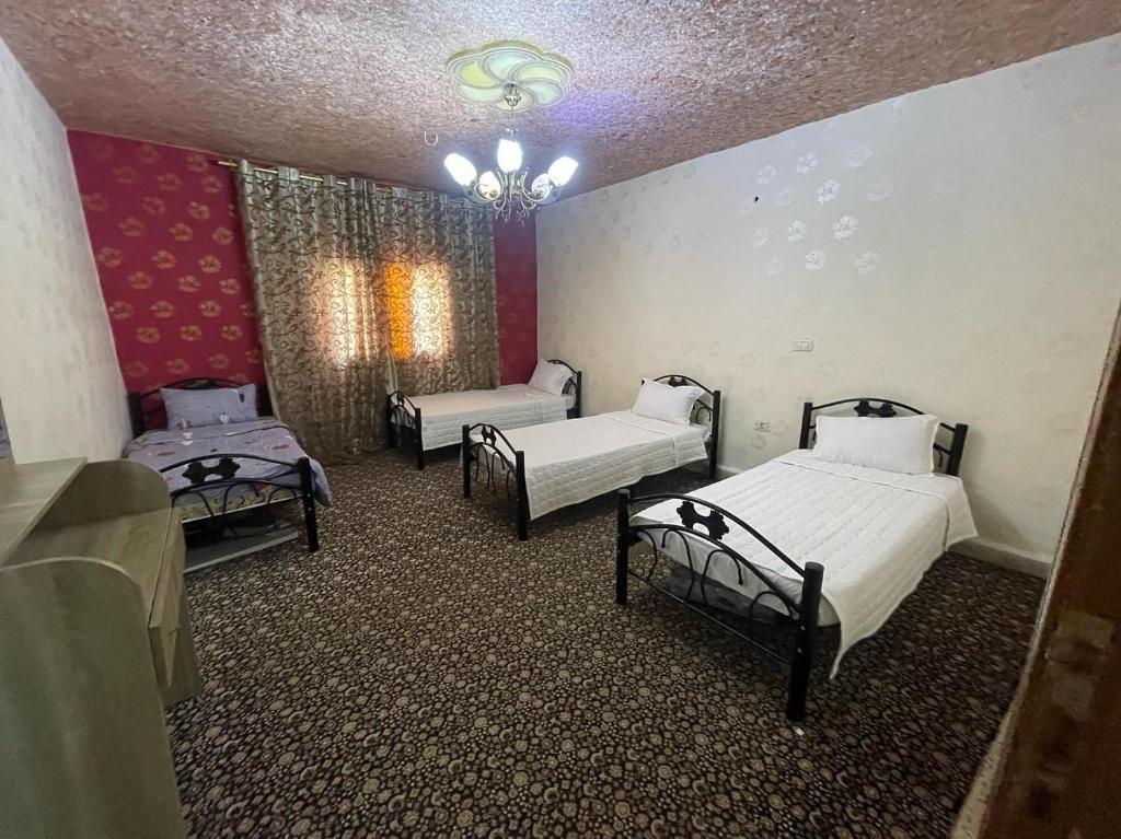 a room with three beds and a chandelier at Nabatean NIghts Home Stay in Wadi Musa