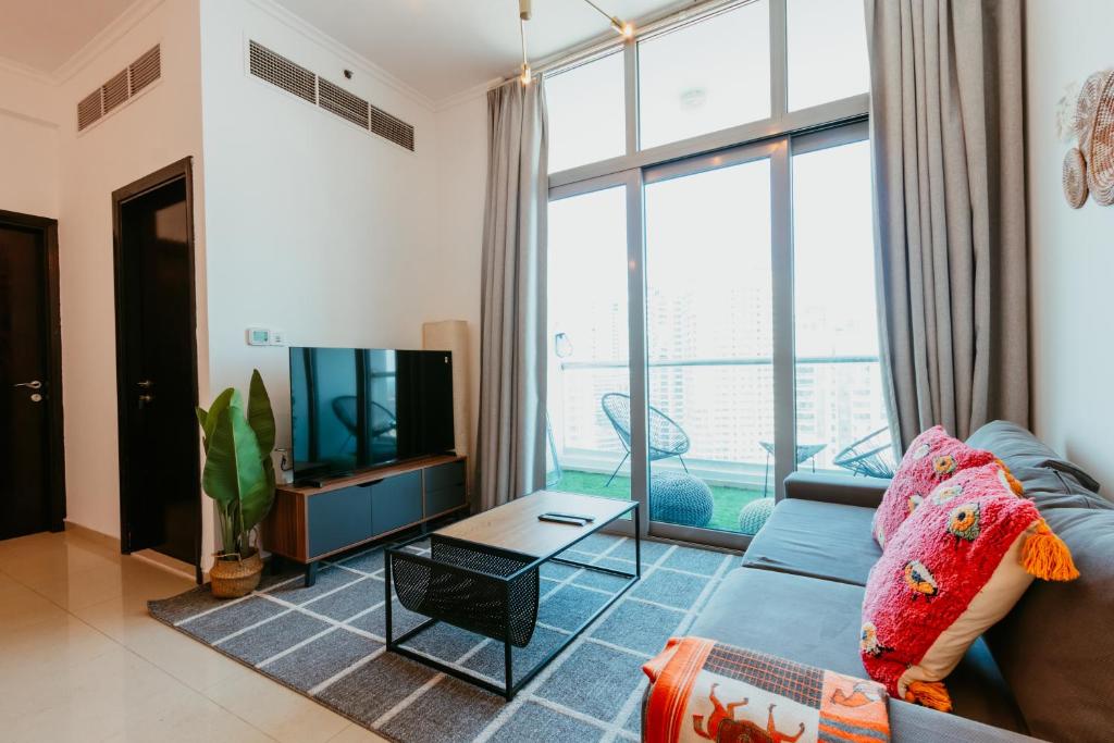 a living room with a blue couch and a tv at Cozy 1 BR in Dubai Marina in Dubai