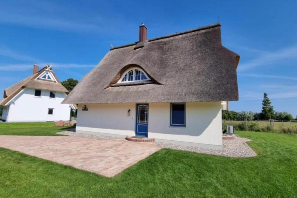 a small white house with a thatched roof at Wippezogel - Ferienhaus mit Sauna und Kamin für bis zu 8 Personen in Pepelow