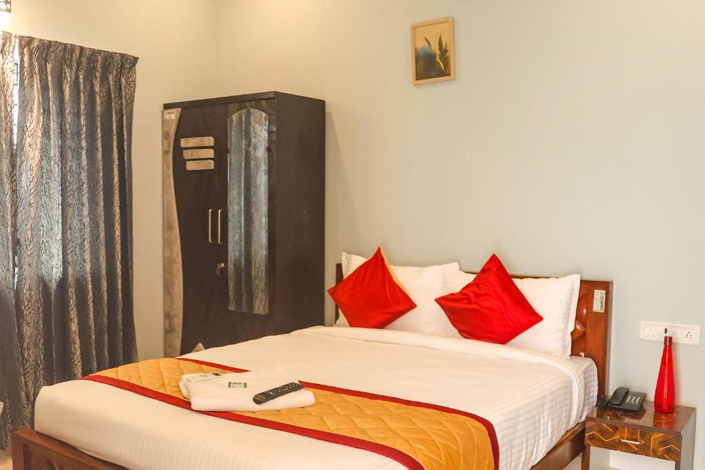 1 dormitorio con 1 cama con almohadas rojas en FabHotel Home Tree Service Apartment Kolathur en Chennai