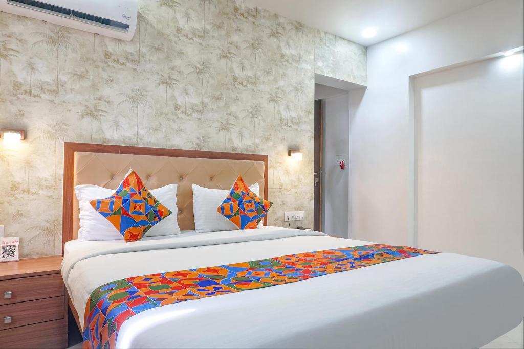 1 dormitorio con 1 cama grande y almohadas coloridas en FabHotel Emersion Residency, en Pune