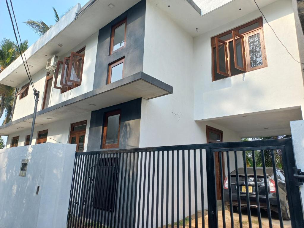 ein weißes Haus mit einem schwarzen Zaun davor in der Unterkunft Villa paddy feild in Hiripitiya