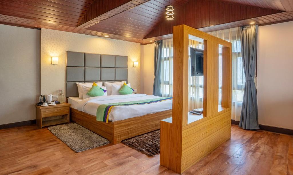a bedroom with a large bed and a window at Treebo Trend Eeshan Rodhi Resort - Darjeeling in Darjeeling