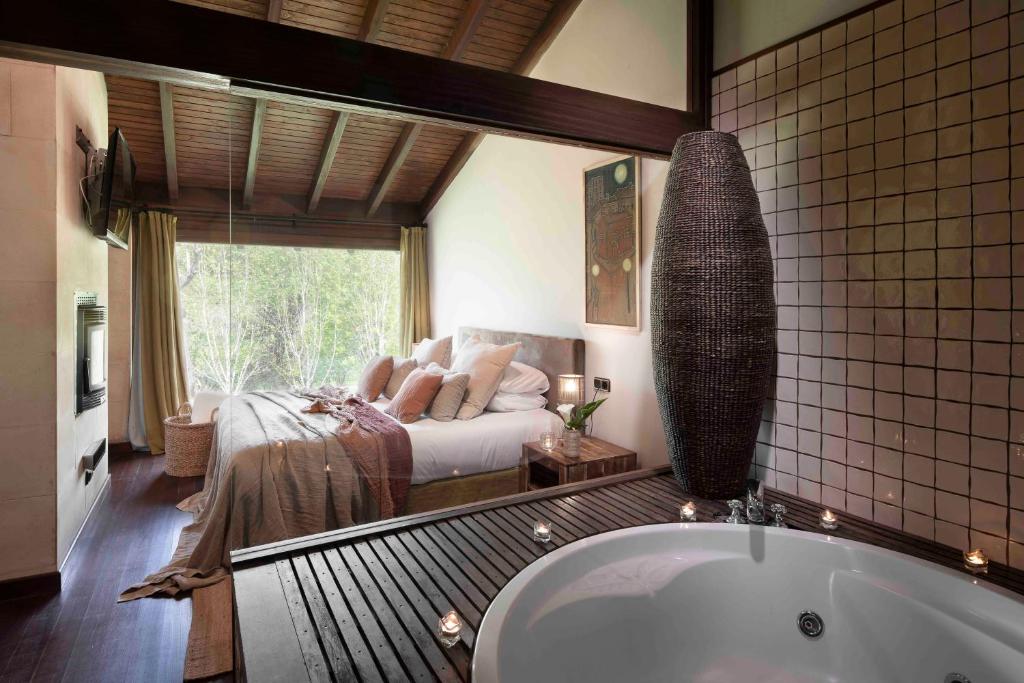 ein Bad mit Badewanne und ein Bett in einem Zimmer in der Unterkunft La Corte de Lugás in Lugás