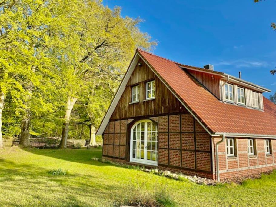 a house with a red roof on a green field at Urlaub mit Hund im Ferienhaus am Wingster Wald in Wingst