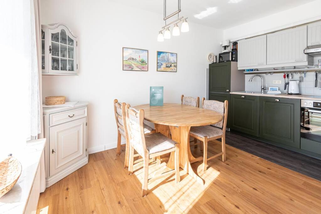 a kitchen with a wooden table and chairs at Sonnige Ferien im Nordseegruß 2 in Wenningstedt