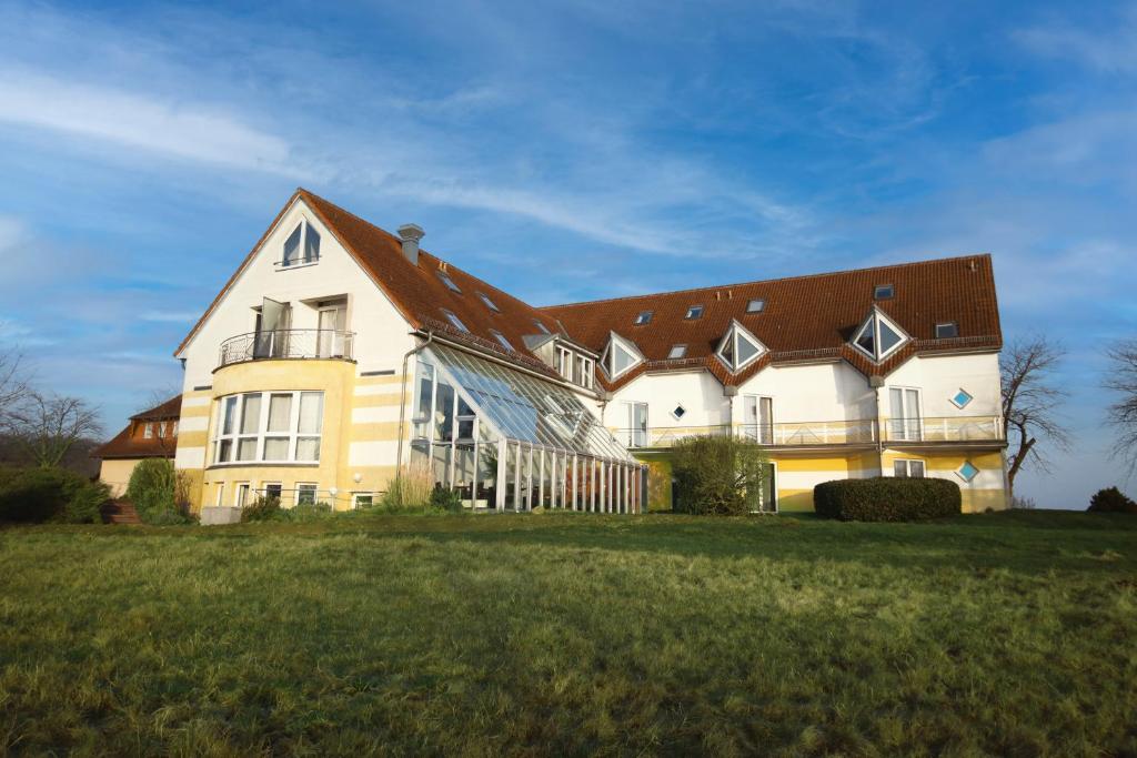 ein großes weißes Gebäude mit braunem Dach in der Unterkunft Inselhotel kleiner Bodden in Buschvitz