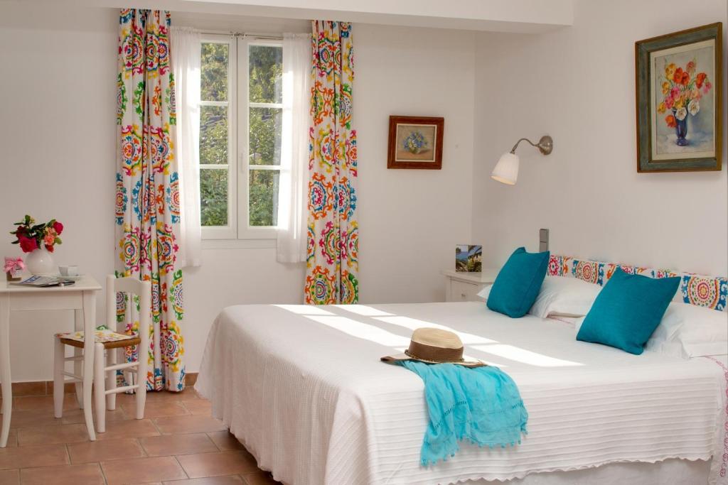 a bedroom with a large white bed with blue pillows at La Ferme D'Augustin in Saint-Tropez