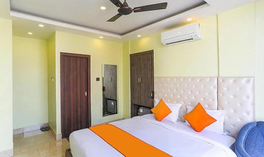 een slaapkamer met een bed met oranje kussens en een plafond bij FabHotel Aspiring Inn in Calcutta