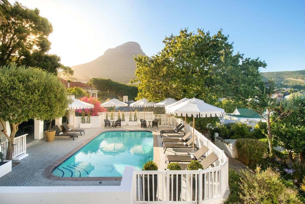 una piscina con sillas y sombrillas con una montaña en el fondo en One Kensington Boutique Hotel, en Ciudad del Cabo