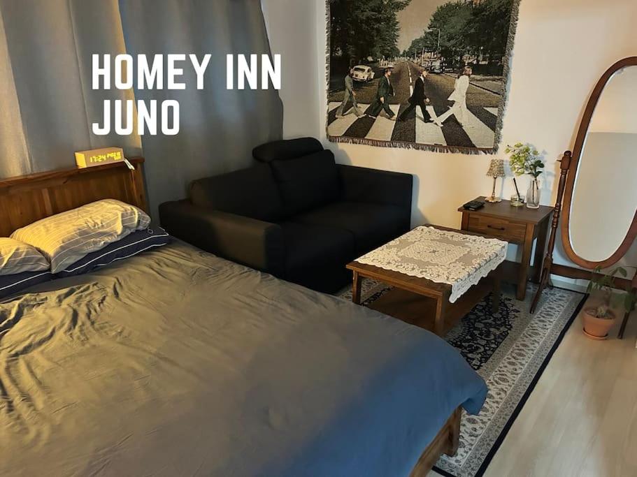 a bedroom with a bed and a couch and a chair at Homey inn Juno in Suwon