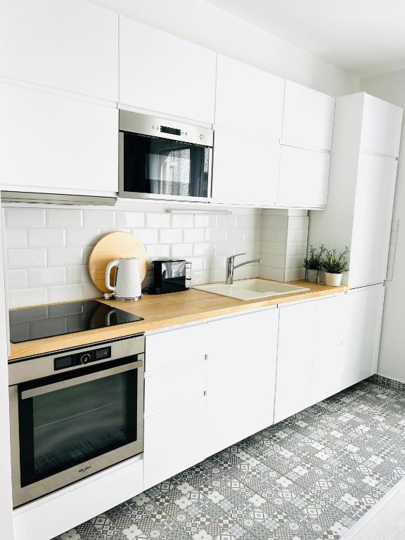 Biała kuchnia z białymi szafkami i zlewem w obiekcie Elizabeth Garden Premium Apartment w mieście Kecskemét