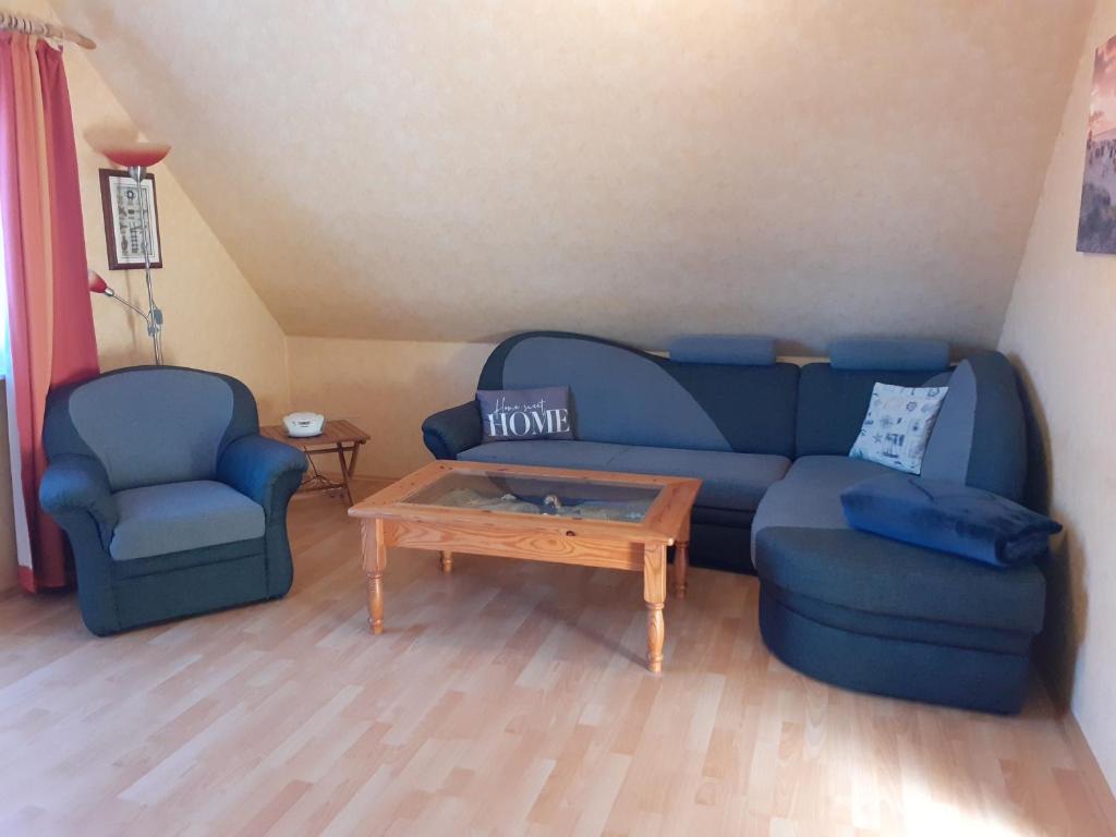 sala de estar con sofá azul y 2 sillas en Balkonwohnung Seestern, en Hooksiel