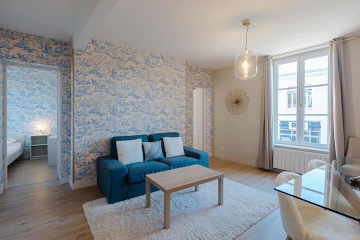 un salon avec un canapé bleu et une table dans l'établissement Le Cabourgeais centre ville, à Cabourg