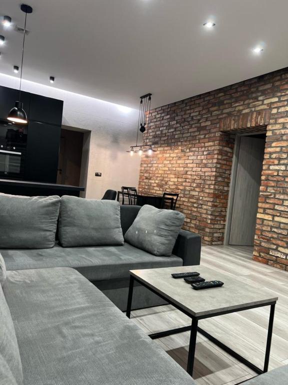 a living room with a couch and a brick wall at Raciborska Royal Apartment - miejsce parkingowe na parkingu strzeżonym in Gliwice