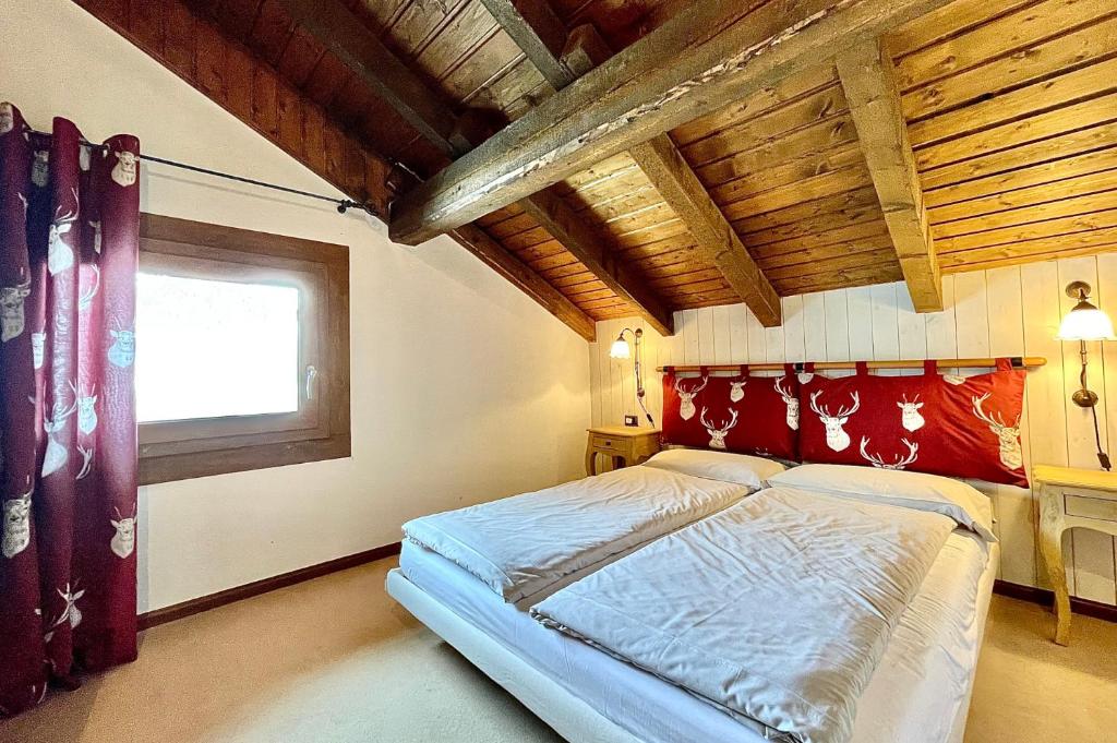 una camera con letto con testiera rossa e finestra di Appartamento Emanuel a Livigno