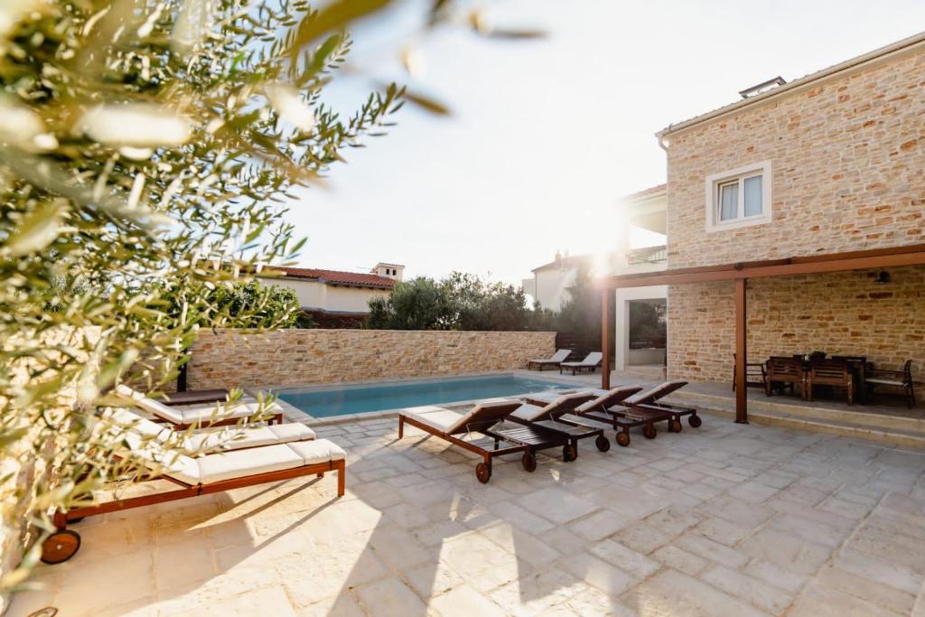 eine Terrasse mit Liegestühlen und ein Swimmingpool in der Unterkunft Olive Tree Apartments 2 in Vodice