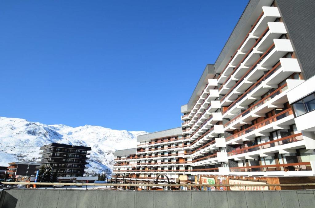 a tall building with snow capped mountains in the background at Résidence Chaviere - Studio pour 2 Personnes 034 in Les Menuires