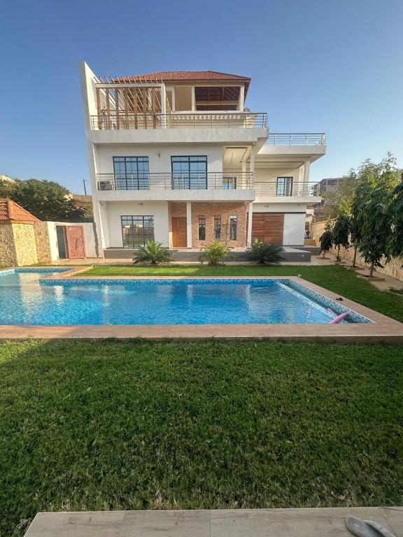 a house with a swimming pool in front of a house at Villa Eve in Rufisque