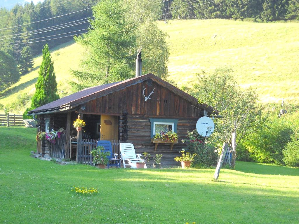 a log cabin with a porch and chairs in a field at Chalet Hansl in Vordernberg