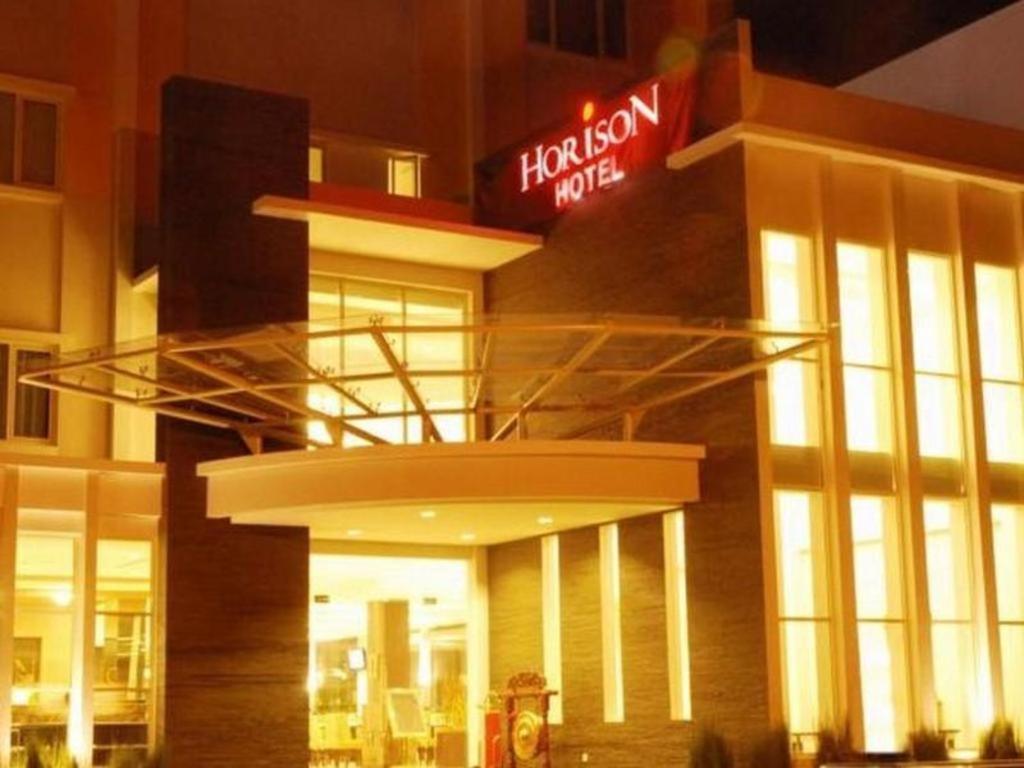 um edifício de hotel com um letreiro de néon vermelho em Hotel Horison Kendari em Puunggolaka