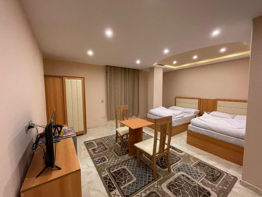a room with two beds and a desk and a television at King Of Pyramids Hotel in Cairo