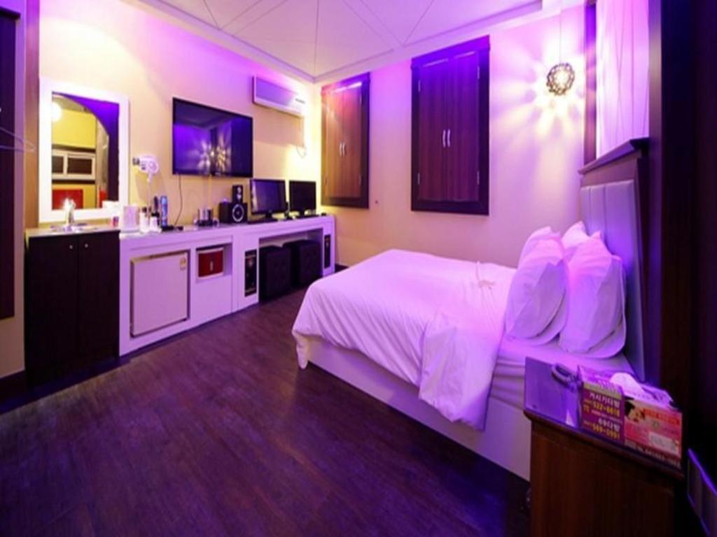 a bedroom with a bed and a kitchen with purple lights at Hotel Vole Cheonan in Cheonan