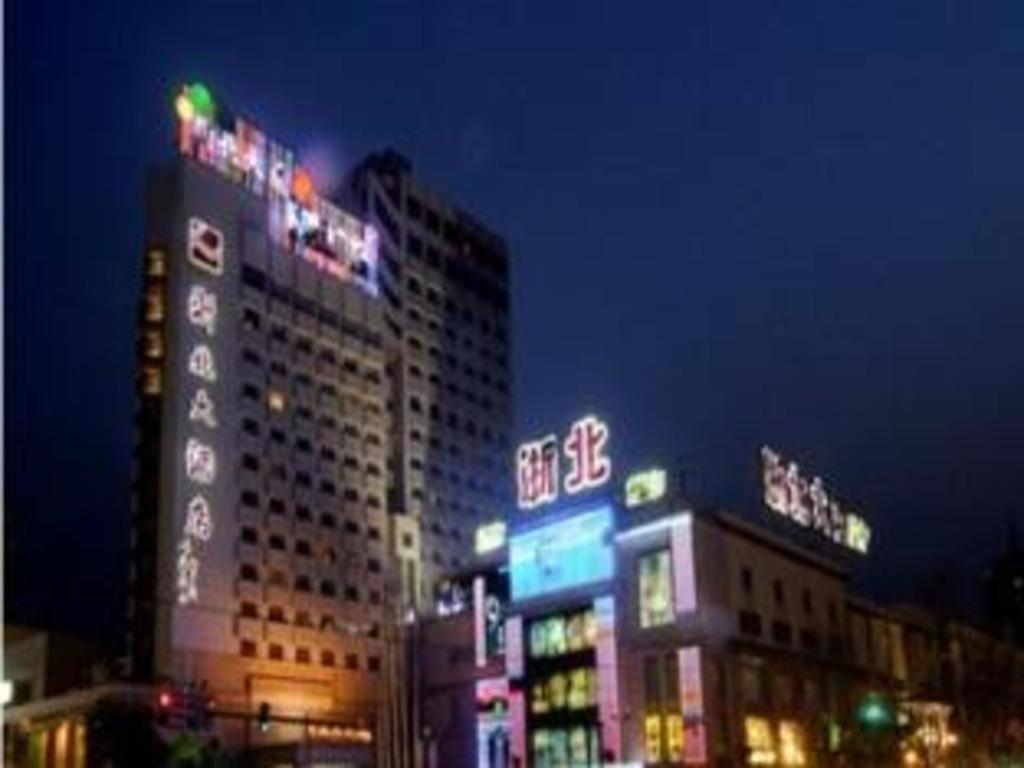 a tall building with neon signs on it at night at Huzhou Zhebei Hotel in Huzhou