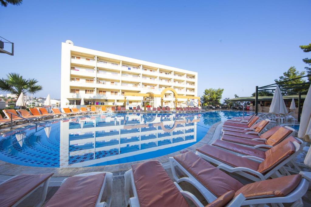 a swimming pool with lounge chairs and a hotel at Tuntas Family Suites Kusadasi in Kuşadası
