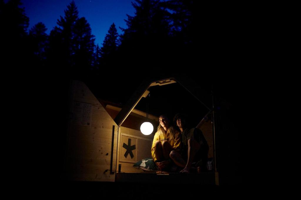 dwoje ludzi siedzących w ciemności pod światłem w obiekcie Camping Marmolada Malga Ciapela w mieście Malga Ciapela