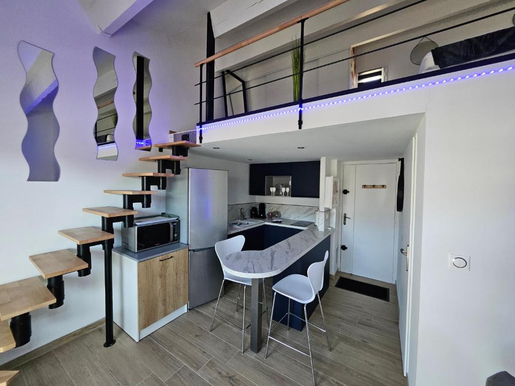 Ce loft comprend une cuisine et un bar avec tabourets. dans l'établissement Cap d'Agde Les Estivales, au Cap d'Agde