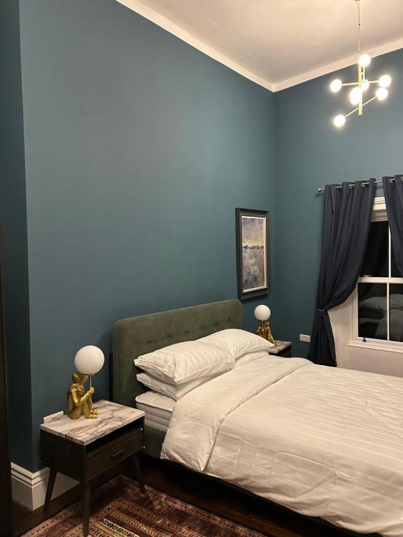 a blue bedroom with a bed and a window at Patrick Street Townhouse in Cork