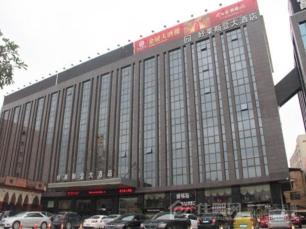 un gran edificio con coches estacionados en un estacionamiento en Quanzhou Jinjiang Hollyston Hotel en Jinjiang