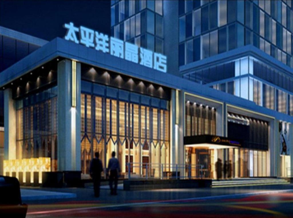 瀋陽市にあるPacific Regency Hotel Shenyangの夜の建物前を歩く二人