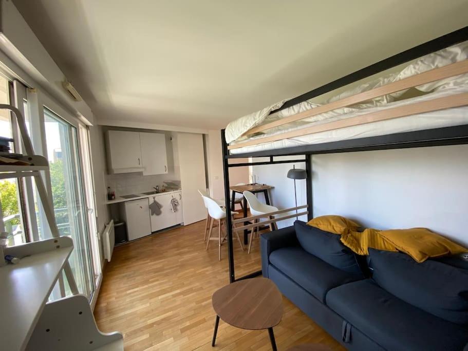 a living room with a blue couch and a loft bed at Beau studio spacieux et calme dans résidence de standing in Boulogne-Billancourt