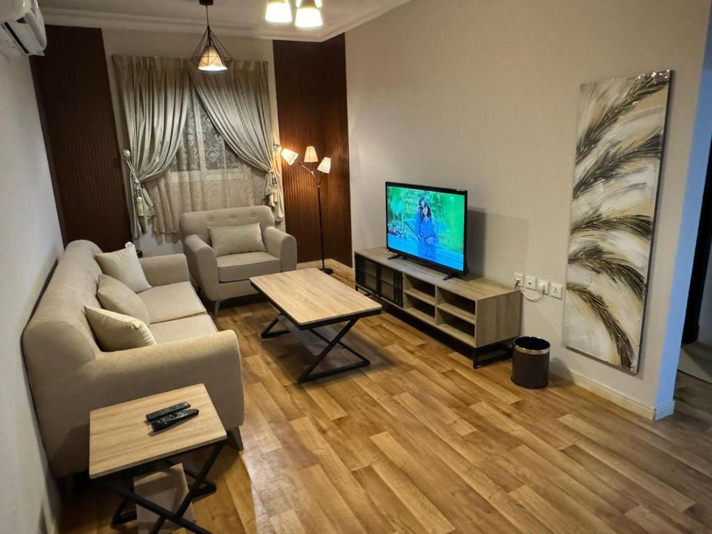 a living room with a couch and a television at شقق روز الفندقية دخول ذاتي in Al Khobar