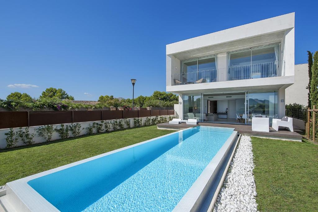 a villa with a swimming pool in front of a house at Villa Barcares in Alcudia