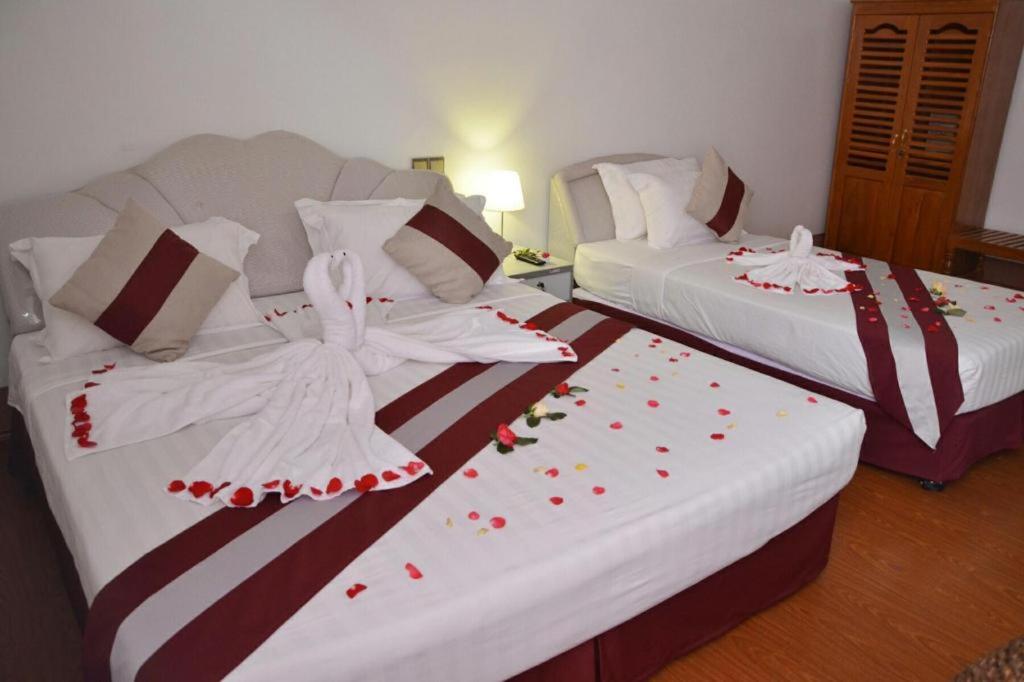 2 łóżka w pokoju hotelowym z różami w obiekcie Mya See Sein Hotel w mieście Myeik