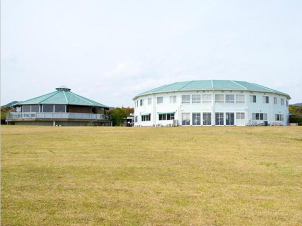 ein großes weißes Gebäude mit einem grünen Dach auf einem Feld in der Unterkunft Nest West Garden Tosa Hotel in Irino