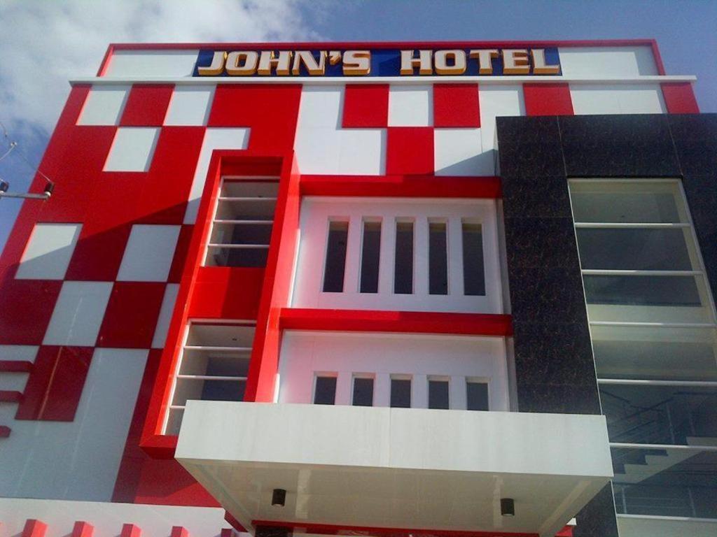 John's Hotel في Maulafa: مبنى احمر وبيض عليه لافته للفندق