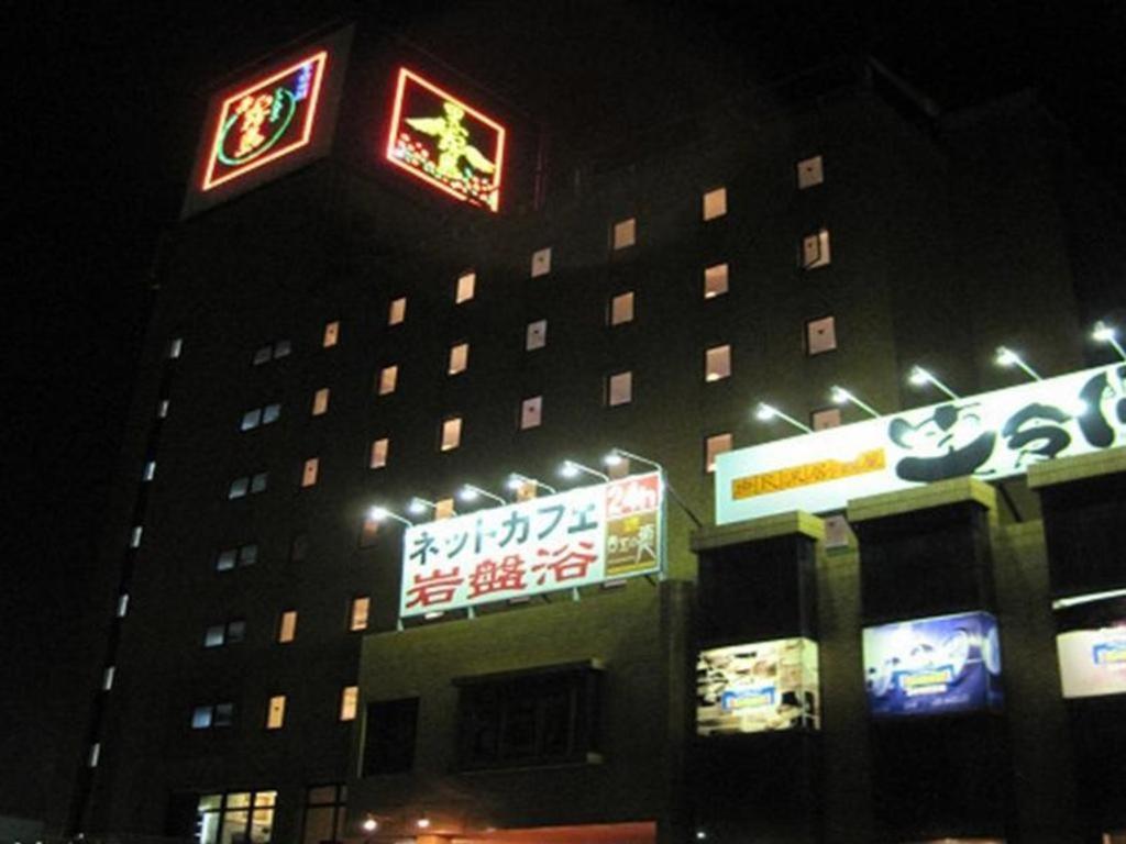 een gebouw met borden aan de zijkant 's nachts bij Miyakonojo Sun Plaza Hotel in Miyakonojo