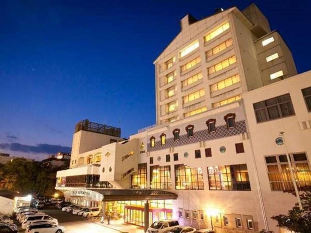 een groot gebouw met auto's geparkeerd op een parkeerplaats bij Yudaonsen Ubl Hotel Matsumasa in Nakaichi