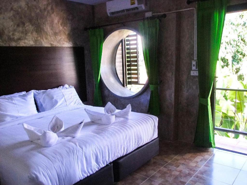 Un dormitorio con una cama con almohadas blancas y una ventana en SabayNan Hotel en Ban Nong Tao